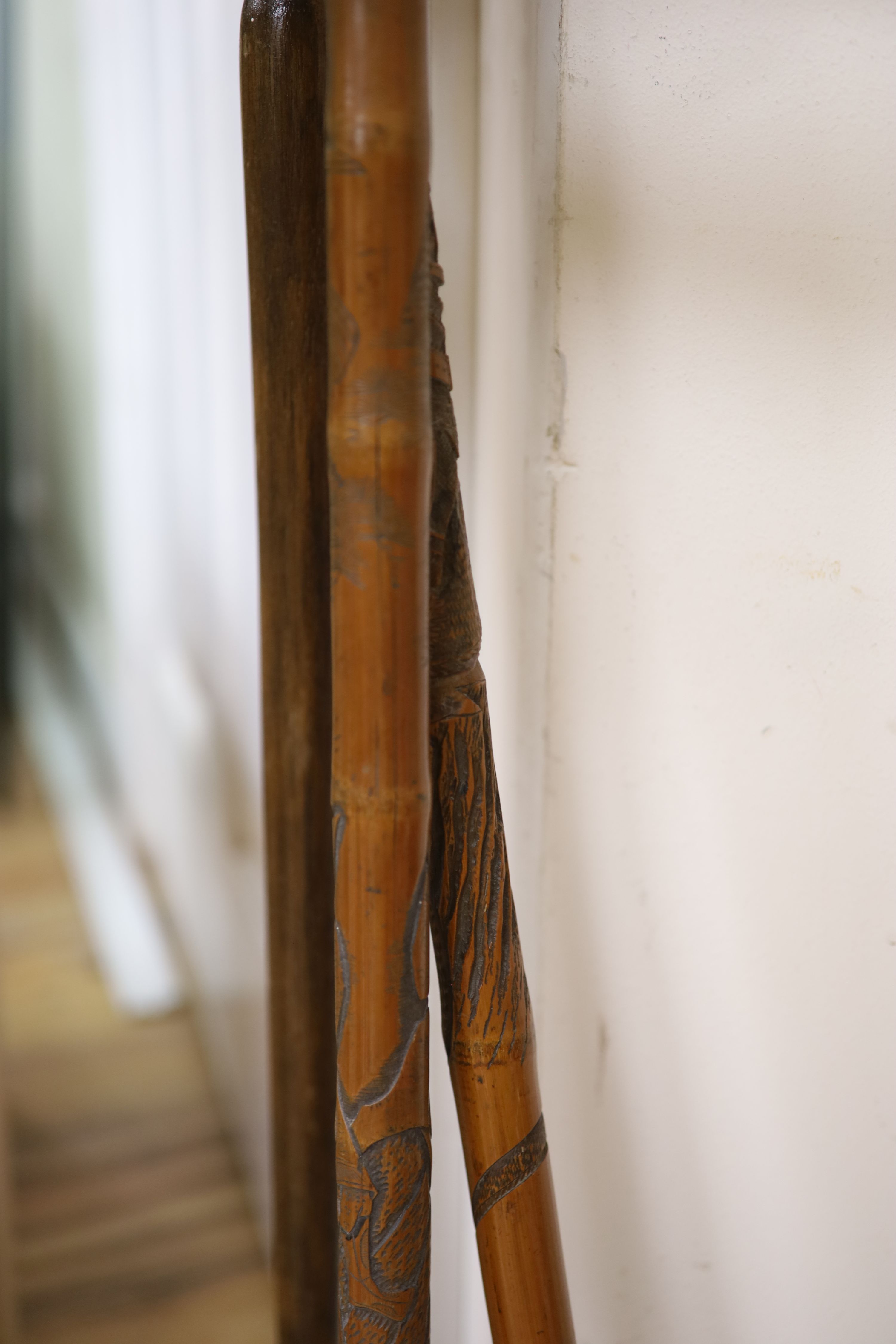 Four Chinese carved wood walking canes, together with a stick stand